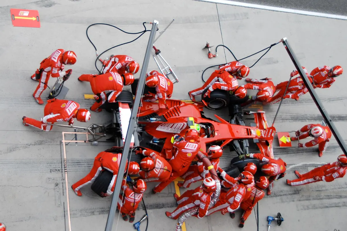 Formula One pit crew swarming a Ferrari during a pit stop